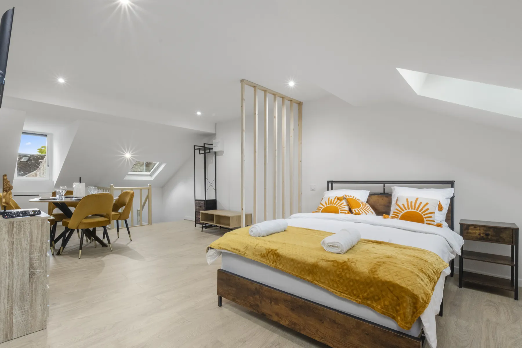Studio meublé lumineux sous combles : lit double, coin repas et fenêtres de toit