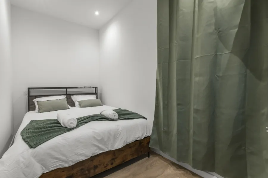 Studio Forêt : lit double et rideaux vert profond, au rez-de-chaussée