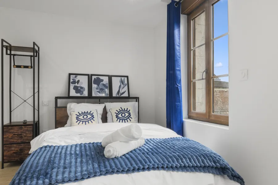Studio Ocean : lit double au plaid bleu, rideaux bleus et fenêtre sur rue, au premier étage